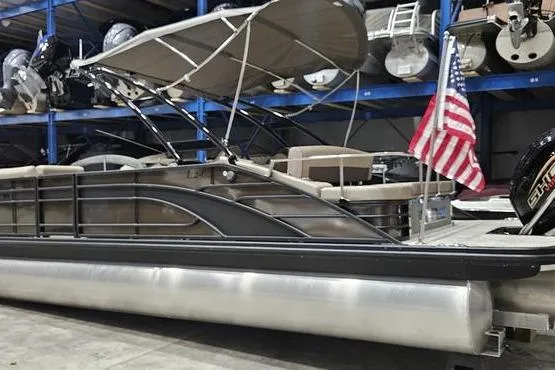 The Image of 2026 Bennington 24 L Swingback pontoon boat with canopy and American flag in a storage facility. - 0