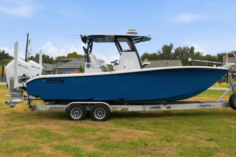 Slide: The Image of 2023 Costa Custom Boats 264 HC on trailer, blue hull, dual engines, parked on grass. - 10