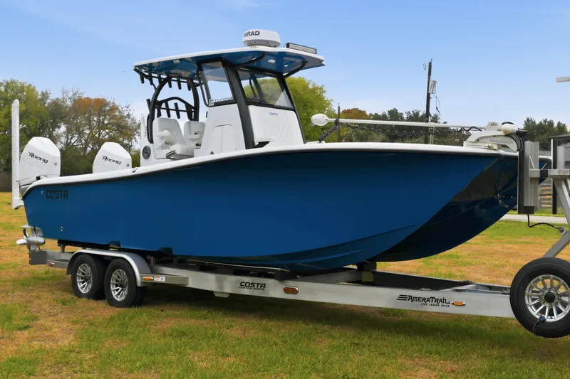 Slide: The Image of 2023 Costa Custom Boats 264 HC on trailer, blue hull, dual engines, outdoor setting. - 11