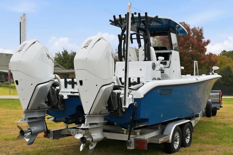 Slide: The Image of 2023 Costa Custom Boats 264 HC with dual engines on a trailer, parked on grass. - 7