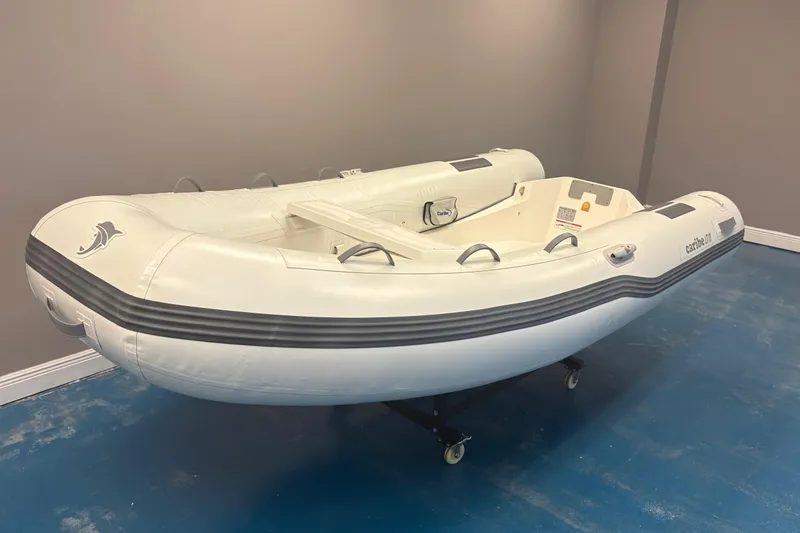 Slide: The Image of 2025 Caribe L-11 inflatable boat with Mercury 20MH motor displayed indoors. - 2
