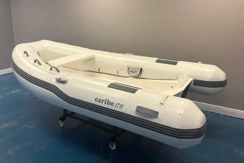 Slide: The Image of 2025 Caribe L-11 inflatable boat with Mercury 20MH engine displayed indoors. - 3