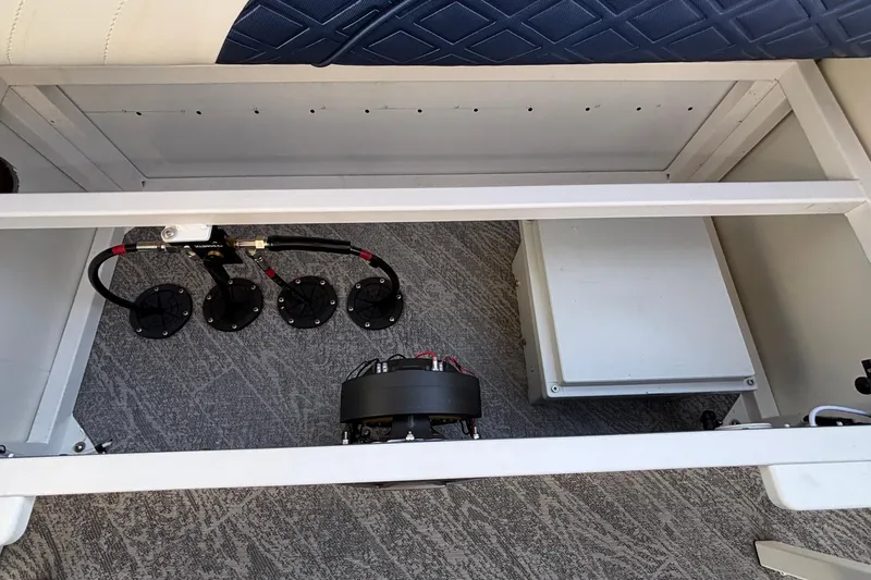 Slide: The Image of Open storage compartment in 2026 JC Sporttoon 26TT boat, showing wiring and components. - 28