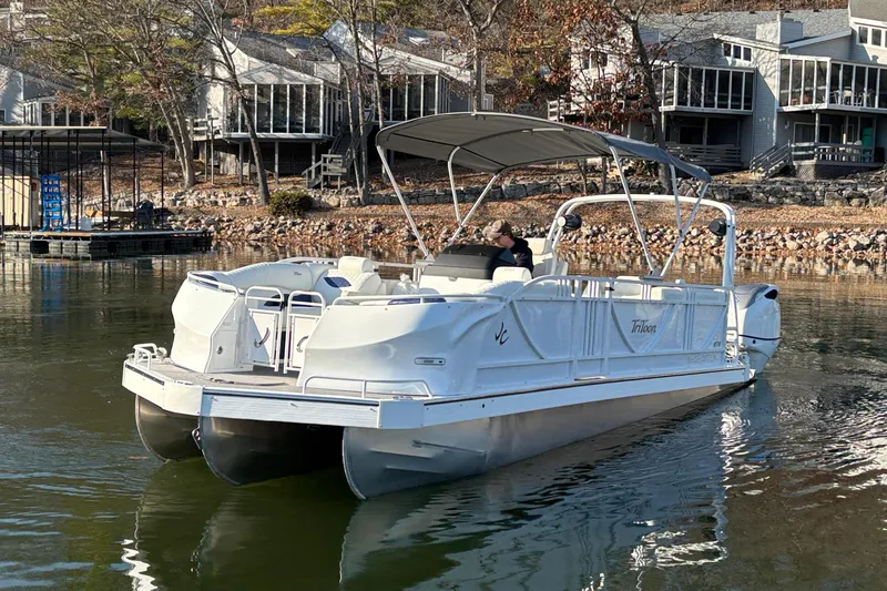 Slide: The Image of 2026 JC Sporttoon 26TT pontoon boat on a calm lake near modern homes. - 8