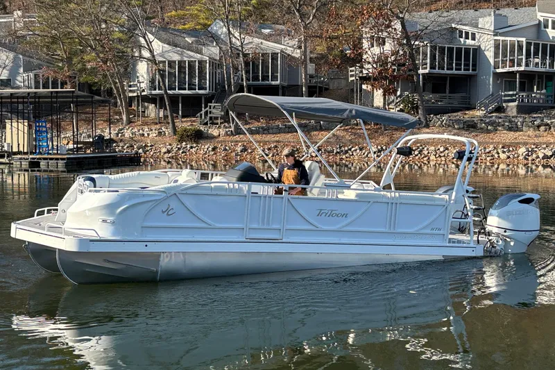 Slide: The Image of 2026 JC Sporttoon 26TT pontoon boat on a calm lake near modern homes. - 7