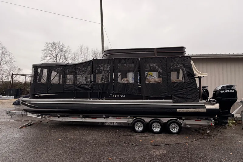 Slide: The Image of 2021 Premier 310 Boundary Waters Rev Top Deck pontoon boat with black canopy on trailer. - 17