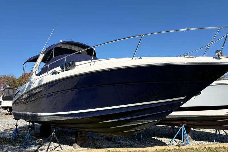 The Image of 2005 Sea Ray 300 Sundancer boat on stands under clear blue sky. - 0