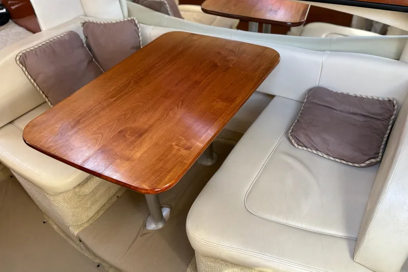 Slide: The Image of Interior dining area of 2005 Sea Ray 300 Sundancer with wooden table and cushioned seating. - 14