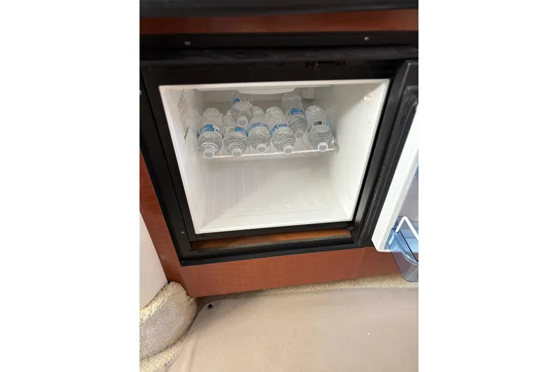 Slide: The Image of Mini fridge with water bottles inside a 2005 Sea Ray 300 Sundancer boat. - 6