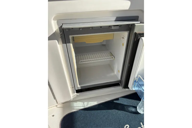 Slide: The Image of Open mini fridge on 2005 Sea Ray 300 Sundancer boat, with a water bottle nearby. - 7