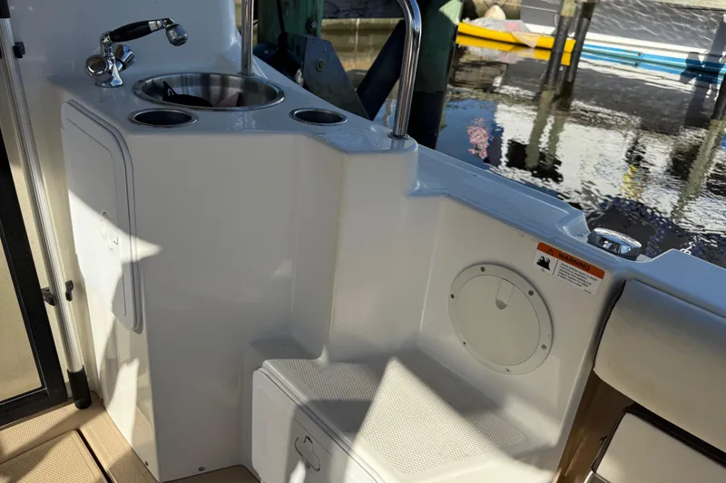 Slide: The Image of 2015 Cutwater 28 boat interior with sink and storage, docked by the water. - 12
