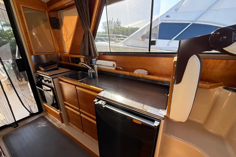 Slide: The Image of 2015 Cutwater 28 boat interior kitchen with wooden cabinets and modern appliances. - 13