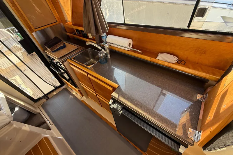 Slide: The Image of 2015 Cutwater 28 boat interior kitchen with sink, stove, and wooden cabinetry. - 14