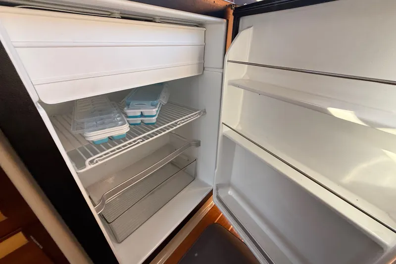 Slide: The Image of Open refrigerator in 2015 Cutwater 28 boat, showing ice trays and empty shelves. - 16