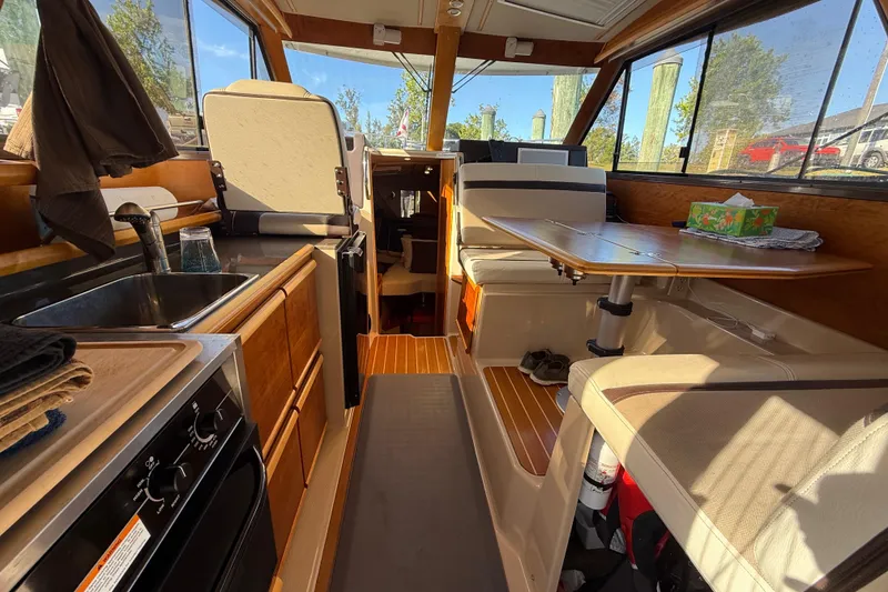 Slide: The Image of 2015 Cutwater 28 interior with kitchen, seating, and table, showcasing wood finishes and natural light. - 18