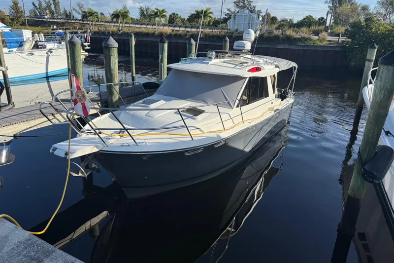Slide: The Image of 2015 Cutwater 28 boat docked at marina, surrounded by calm water and other vessels. - 2