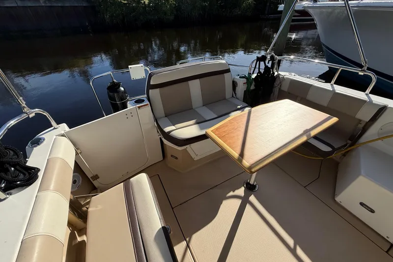 Slide: The Image of 2015 Cutwater 28 boat interior with seating and wooden table on calm water. - 5