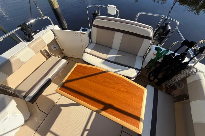 Slide: The Image of 2015 Cutwater 28 boat cockpit with cushioned seating and wooden table. - 7