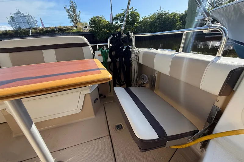 Slide: The Image of 2015 Cutwater 28 boat interior with seating and wooden table, docked outdoors. - 8
