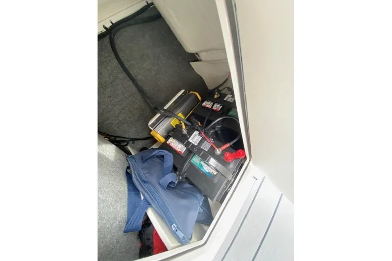 Slide: The Image of 2023 Chaparral 210 SSi boat battery compartment with cables and storage bag. - 17