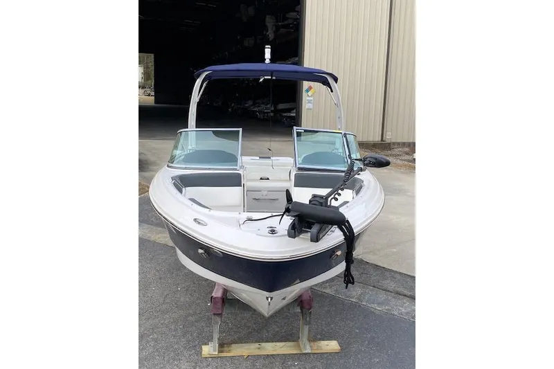 Slide: The Image of 2023 Chaparral 210 SSi boat with blue canopy, docked on a stand. - 4
