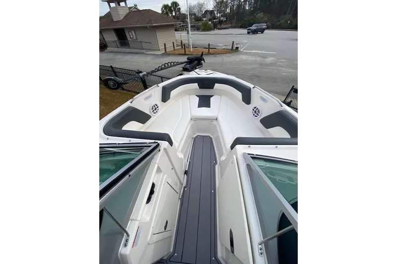 Slide: The Image of 2023 Chaparral 210 SSi boat interior with gray and white seating, docked outdoors. - 9