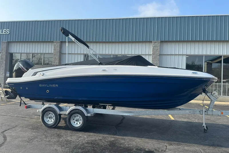The Image of 2026 Bayliner VR6 Bowrider OB on trailer, blue hull, parked outside dealership. - 0