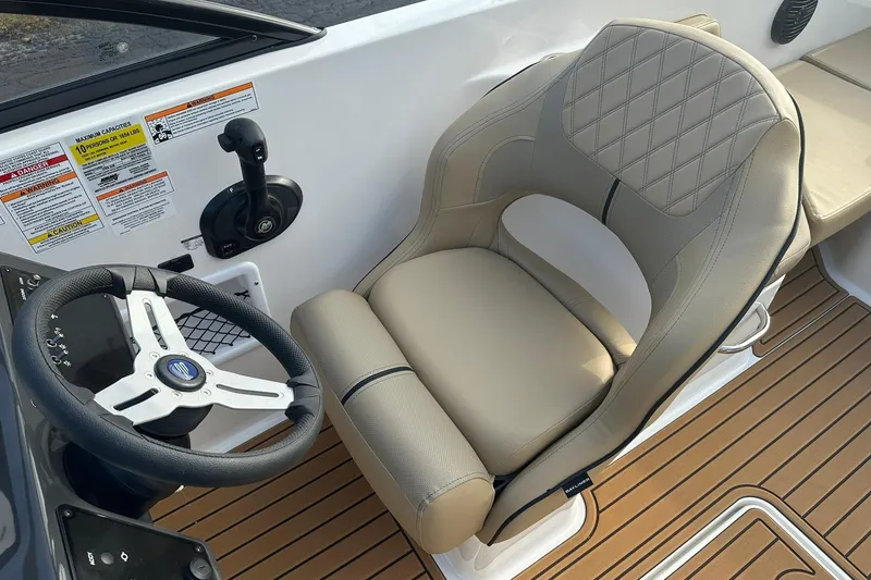 Slide: The Image of 2026 Bayliner VR6 Bowrider OB cockpit with steering wheel and beige captain's chair. - 8