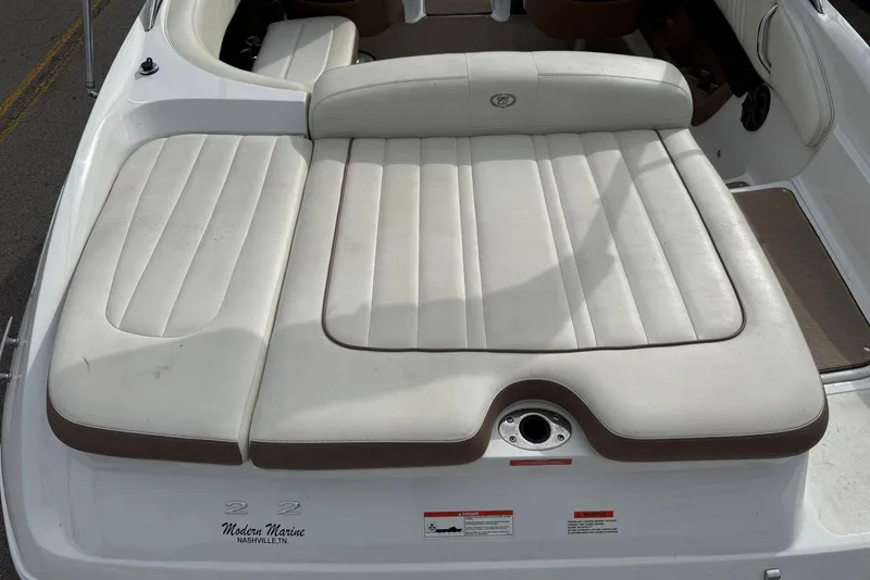 Slide: The Image of 2013 Cobalt 232 boat with white cushioned seating and brown accents. - 23