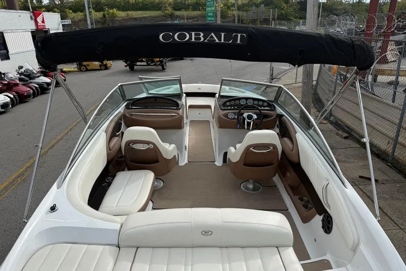 Slide: The Image of 2013 Cobalt 232 boat interior with white and brown seating, steering wheel, and dashboard. - 25