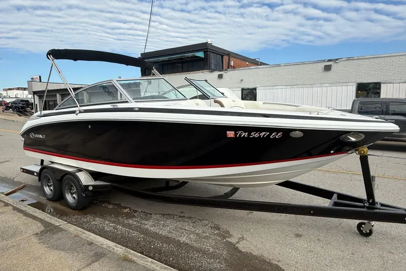 Slide: The Image of 2013 Cobalt 232 boat on trailer, black hull, parked on street. - 9