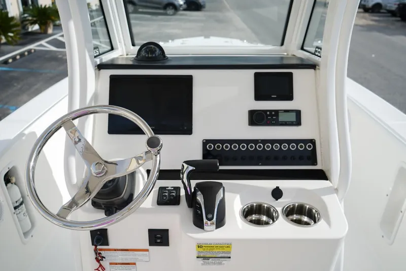 Slide: The Image of Edgewater 230CC 2021 boat console with steering wheel, controls, and cup holders. - 7