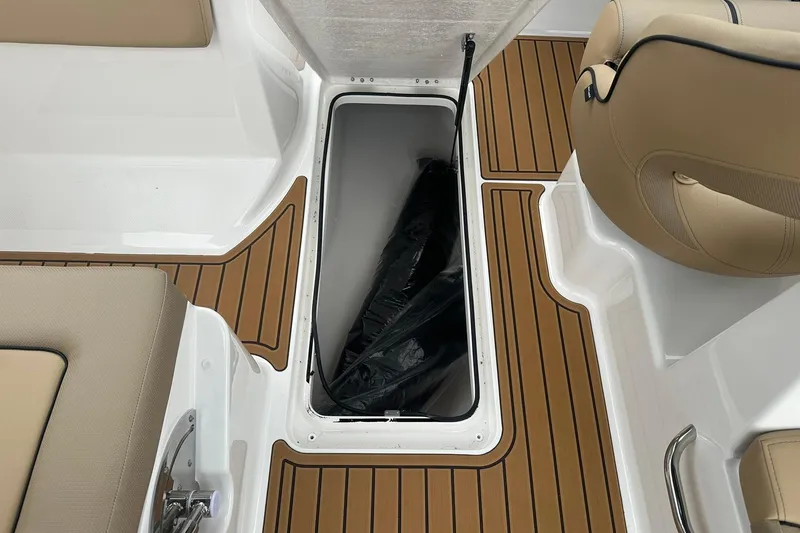 Slide: The Image of 2025 Bayliner VR6 Bowrider OB interior with storage compartment and tan seating. - 18