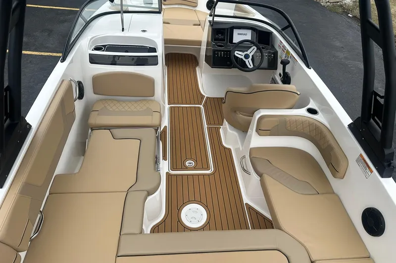 Slide: The Image of 2025 Bayliner VR6 Bowrider OB interior with tan seating and wood-style flooring. - 6