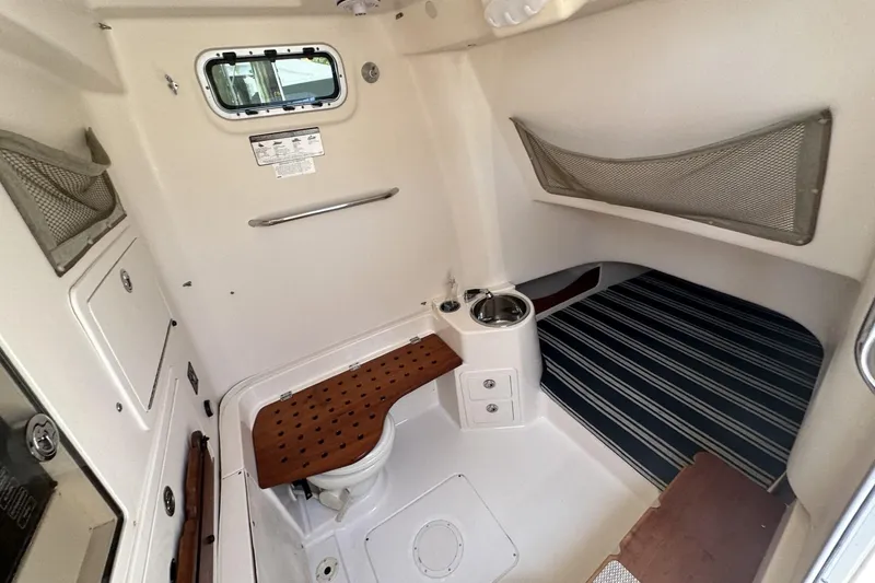 Slide: The Image of 2014 Grady-White Canyon 336 cabin interior with striped bedding and compact amenities. - 33