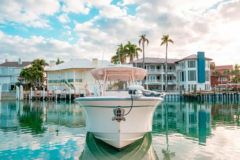Slide: The Image of 2014 Grady-White Canyon 336 boat docked near waterfront homes under a blue sky. - 4