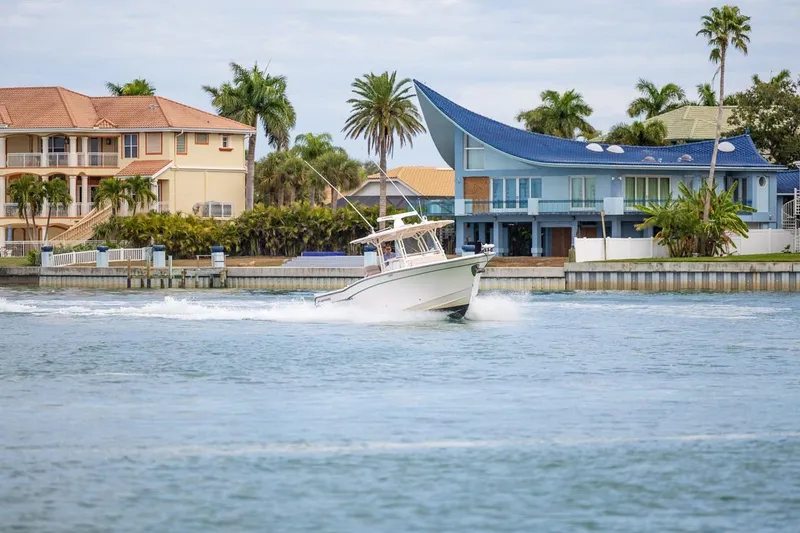 Slide: The Image of 2014 Grady-White Canyon 336 boat cruising near waterfront homes with palm trees. - 46