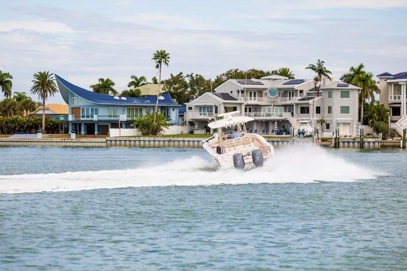 Slide: The Image of 2014 Grady-White Canyon 336 boat cruising near waterfront homes with palm trees. - 52