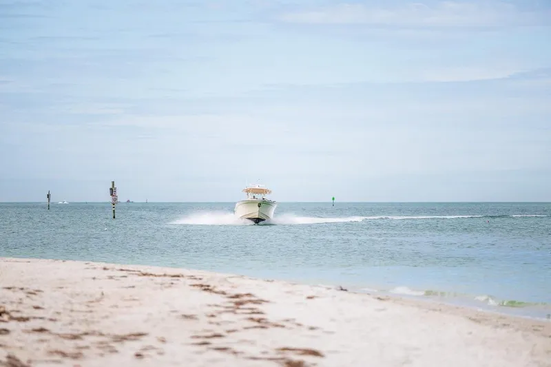 Slide: The Image of 2014 Grady-White Canyon 336 boat cruising on open water near sandy beach. - 55