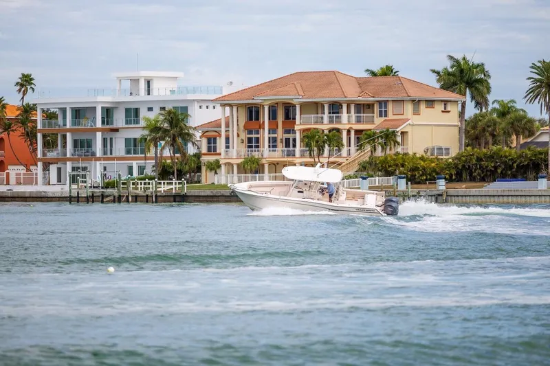 Slide: The Image of 2014 Grady-White Canyon 336 boat cruising near waterfront homes and palm trees. - 57