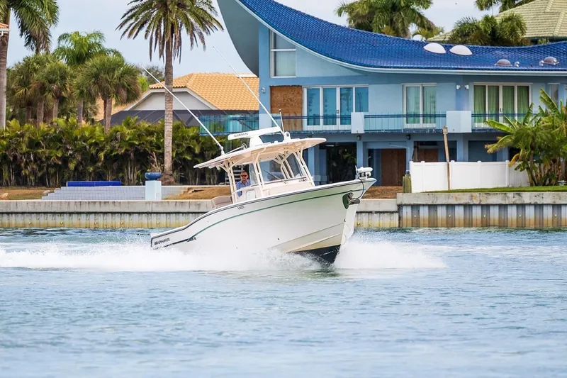 Slide: The Image of 2014 Grady-White Canyon 336 boat cruising near waterfront homes and palm trees. - 7