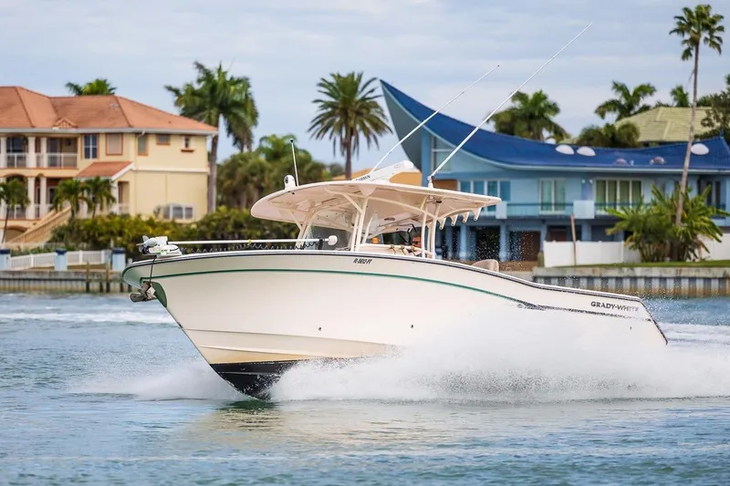 Slide: The Image of 2014 Grady-White Canyon 336 boat cruising near waterfront homes, palm trees in background. - 8