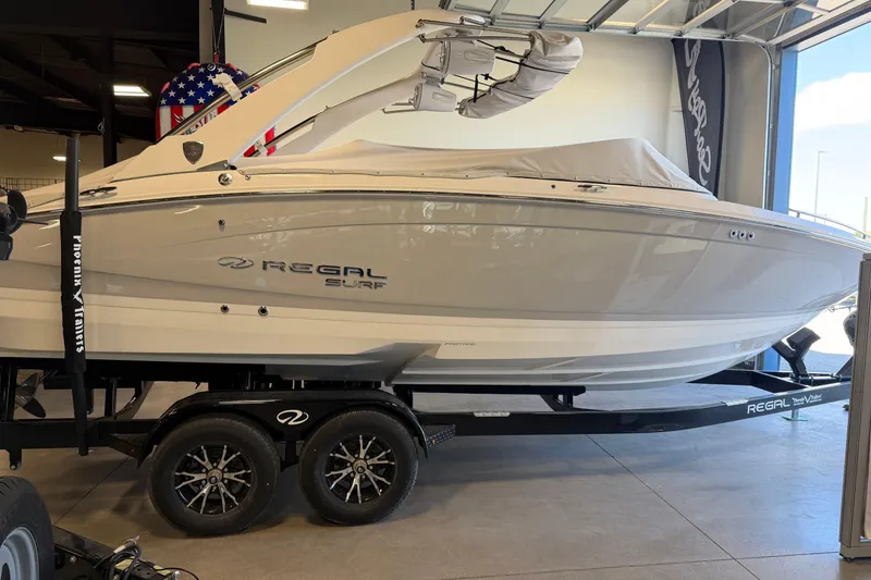 Slide: The Image of 2026 Regal LS6 Surf boat on trailer in showroom, side view. - 7