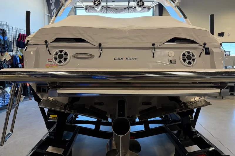 Slide: The Image of 2026 Regal LS6 Surf boat in showroom, rear view with cover and speakers. - 8