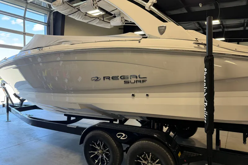 Slide: The Image of 2026 Regal LS6 Surf boat on trailer in showroom. - 9