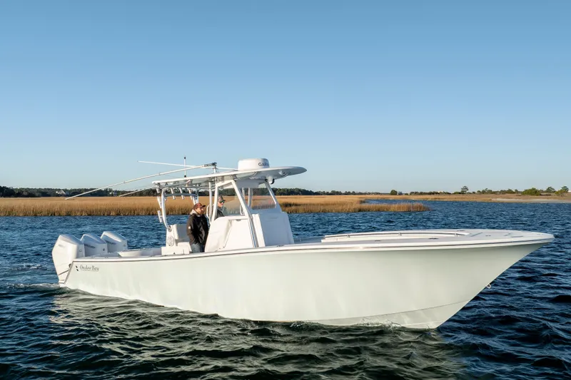 Slide: The Image of 2024 Onslow Bay 33 TE boat cruising on a calm waterway under clear blue skies. - 6