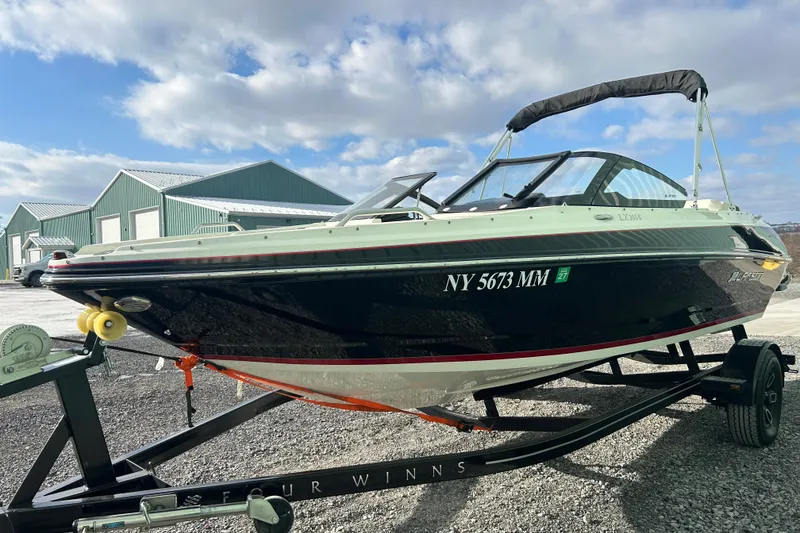Slide: The Image of 2016 Larson LX 205S IO boat on trailer, parked outdoors under cloudy sky. - 10