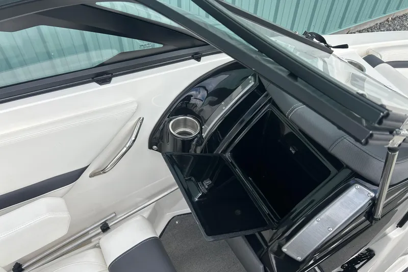 Slide: The Image of 2016 Larson LX 205S IO boat interior with open storage compartment and cup holder. - 20