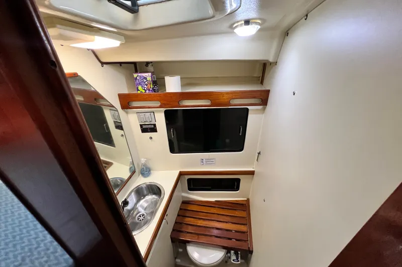 Slide: The Image of 1990 Hunter Legend 40 yacht bathroom with sink, mirror, and wooden accents. - 40