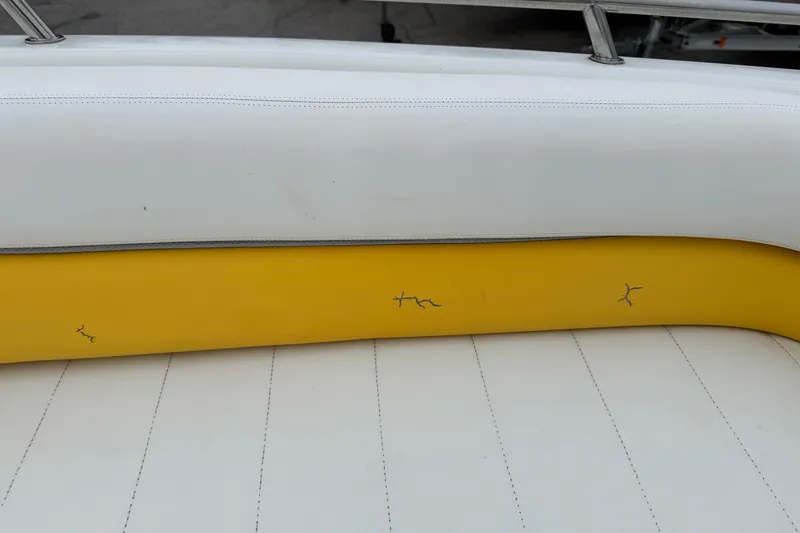 Slide: The Image of 2003 VIP Deckliner 224 boat seat with yellow and white upholstery, showing visible cracks. - 29